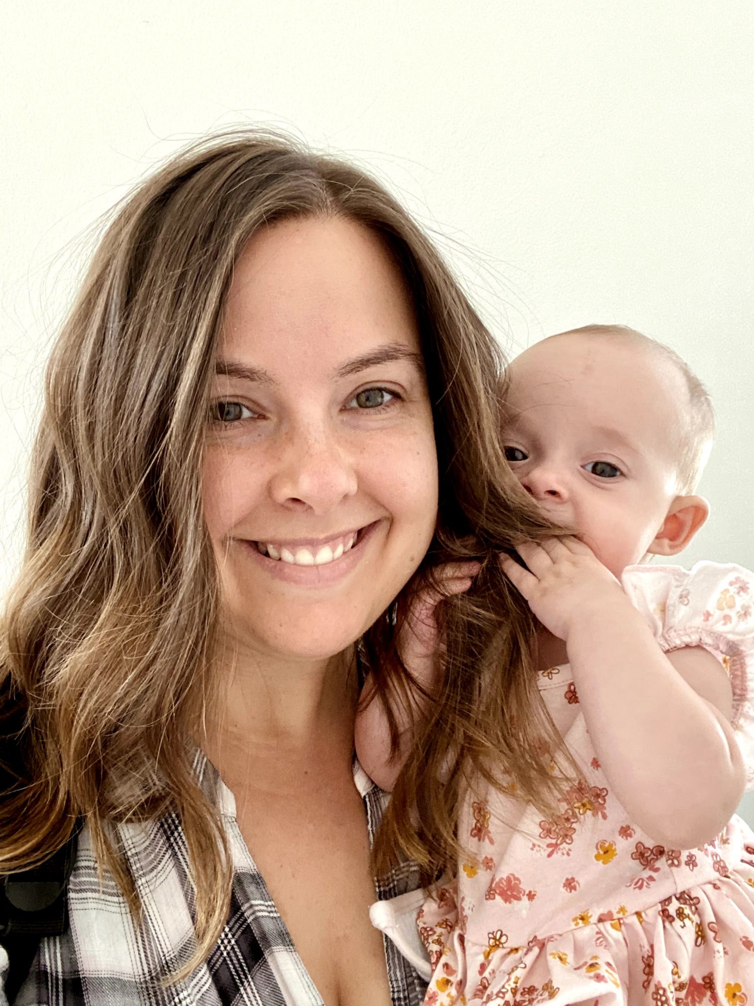 A smiling woman is holding a baby.